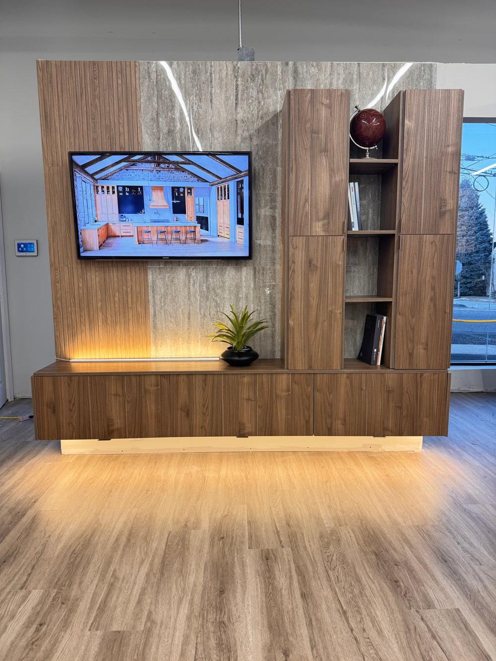 Wooden entertainment console with a television embedded in a room with marble walls.